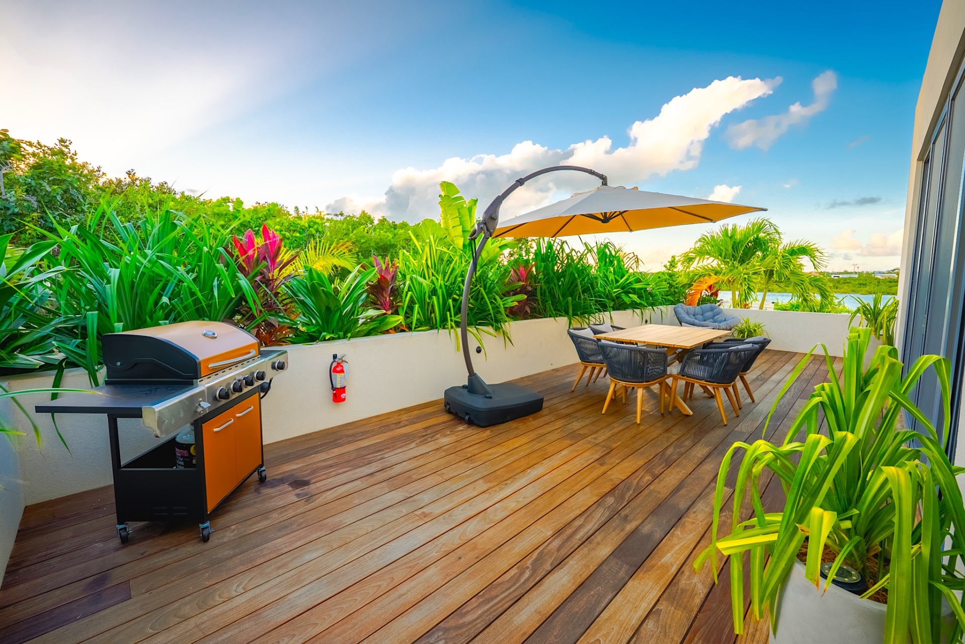 Front deck with BBQ grill, cantilever umbrella, and lush tropical landscaping