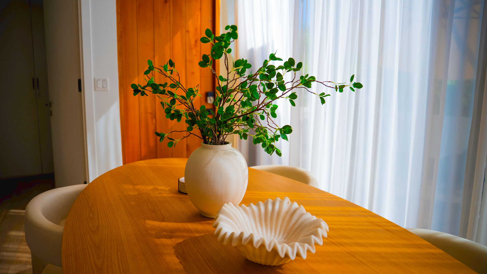 Sunlit dining table with tropical greenery and sculptural decor at Villa Cyan