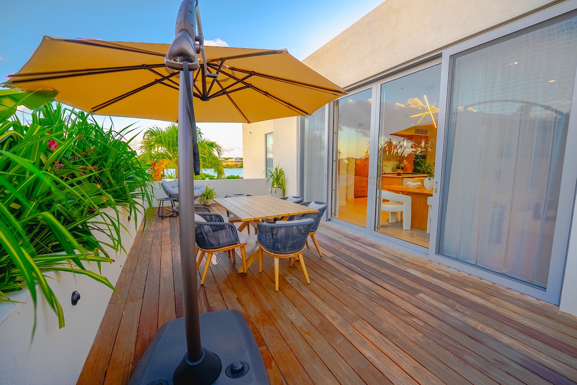 Front deck dining area with yellow umbrella, teak table, and lake views