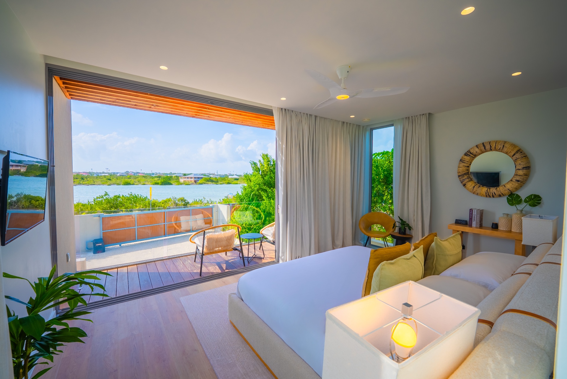 Master bedroom with open sliding doors framing a lake and water view